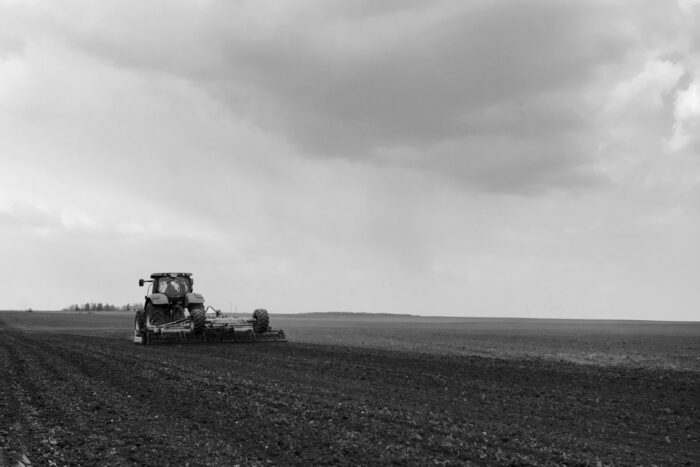Plowed field by tractor in black soil on open countryside nature, tractor in plowed field, soil to growing tasty vegetables, organic plowed field under the clean dark sky is natural soil for tractor